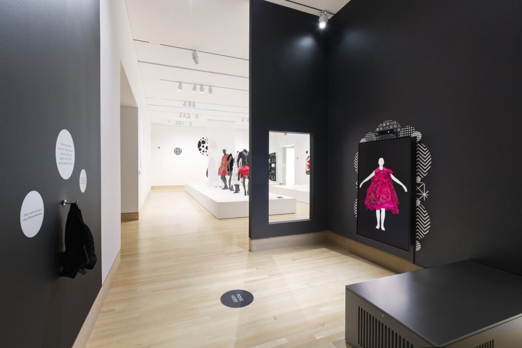 Exhibition with black walls and an interactive Virtual Dressing Room for visitors.