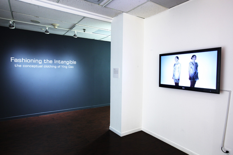 Exhibition with exhibition title in text on the wall and television screen.