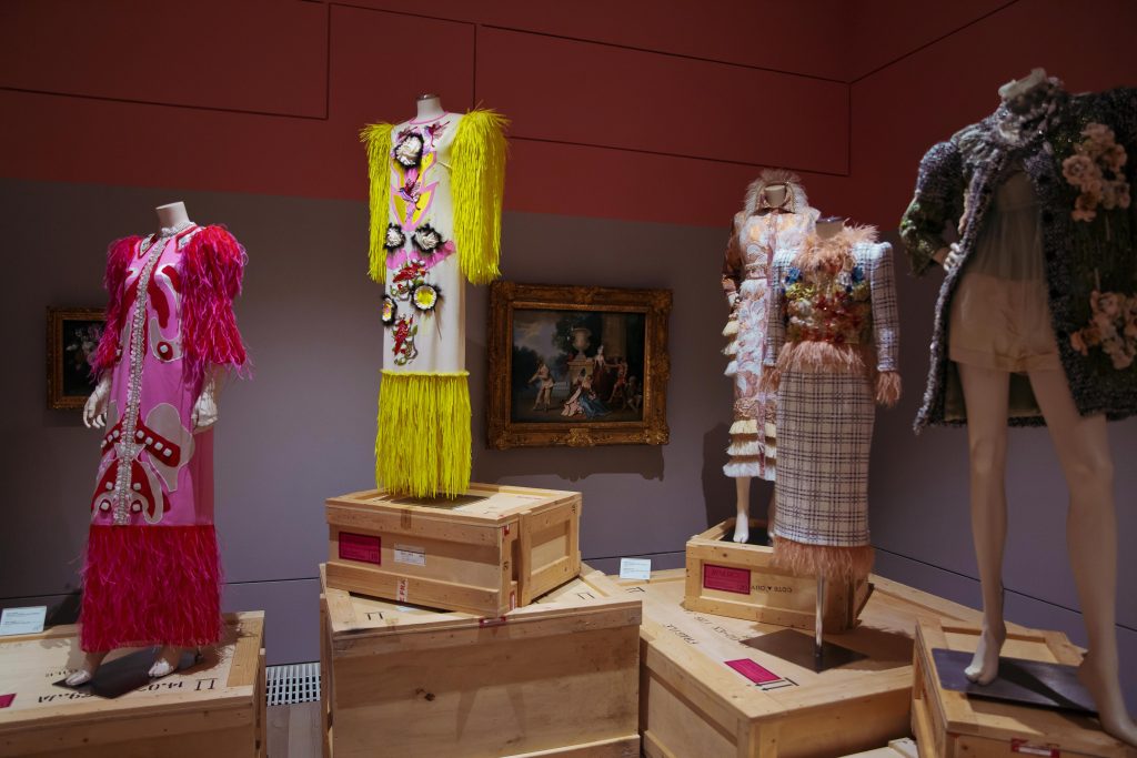 exhibition mannequins displayed on crates next to art