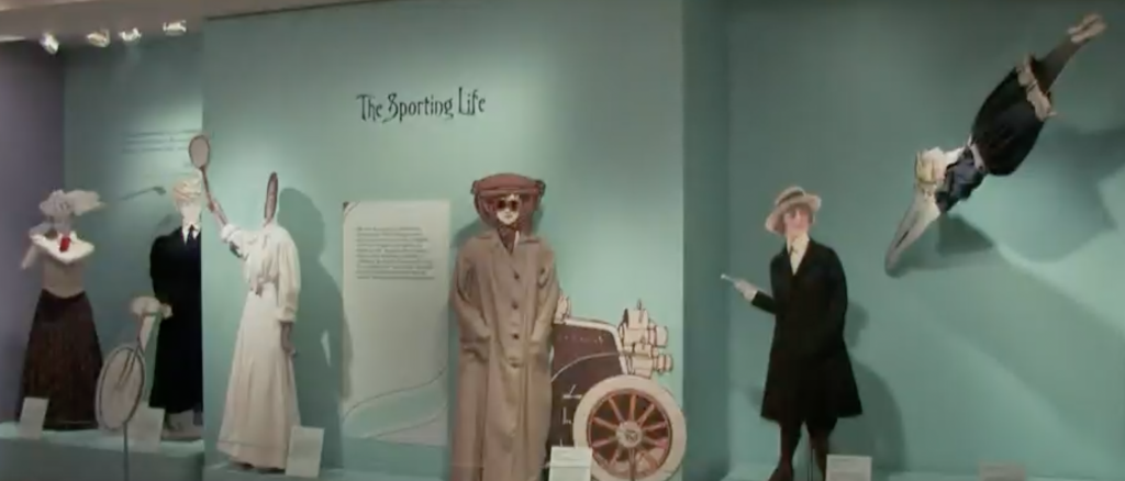 Exhibition with text reading The Sporting Life on the wall and mannequins displaying garments.