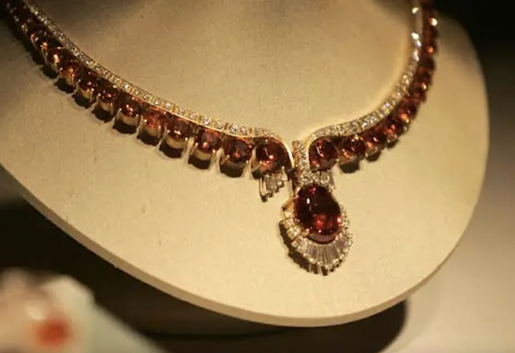 Exhibition with neck bust displaying an 18-inch-long spessarite garnet necklace called the "Ramona Orange".