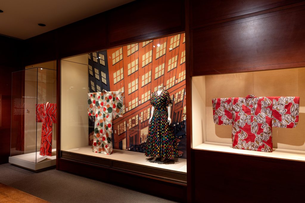 Exhibition with mannequins dressed kimonos behind glass with a patterned background