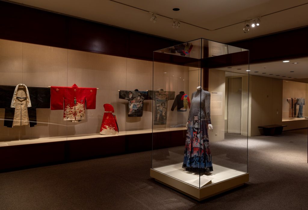 Exhibition with kimonos behind glass with dressed mannequin in foreground