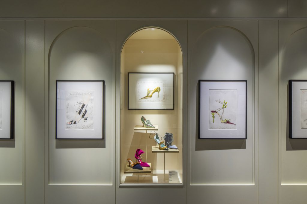 exhibition display of shoes in gallery alcove and illustrations of shoes on wall panels