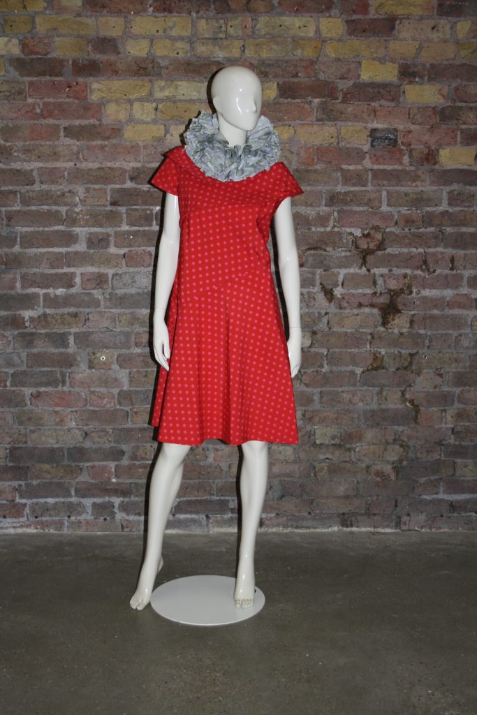 Mannequin in red dress in front of brick wall
