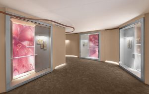 Gallery view of the exhibition, with pink display cases showcasing Van Cleef & Arpels jewellery