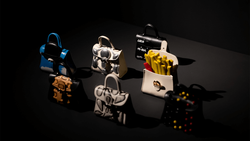 A display of seven handbags, including one with fake french fries, sit against a black backdrop.