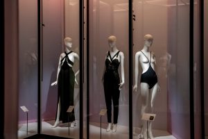 A black dress, playsuit and lingerie worn on white mannequins in a display case.