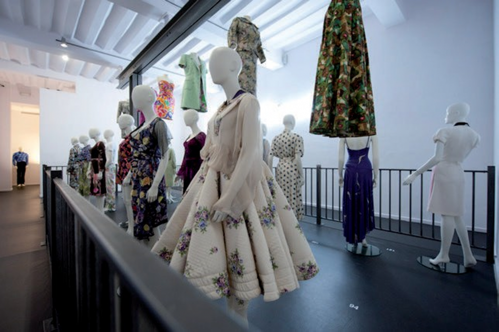 Two rows of women's outfits are worn on mannequins. In between is a row of outfits suspended in the air.