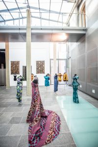 Exhibition view of gallery showing dresses with various African cloths and prints.
