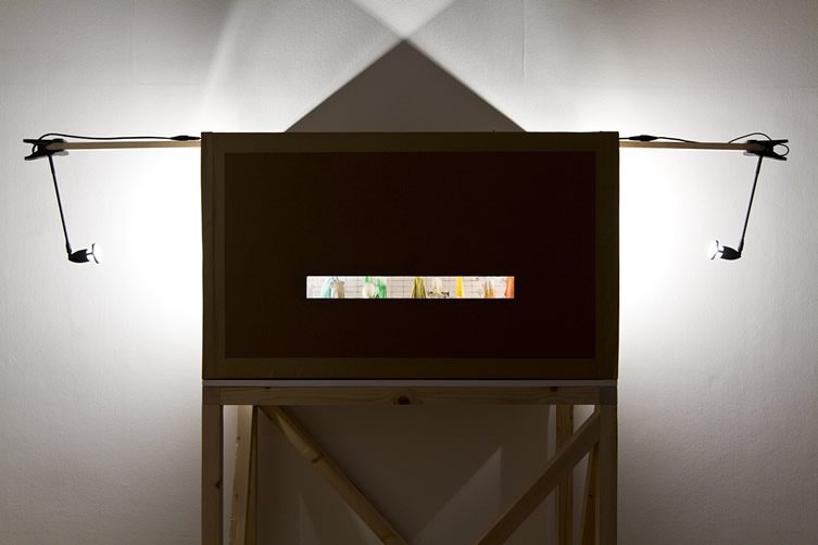 A dark box with cut-out showing an insight into colourful figures inside
