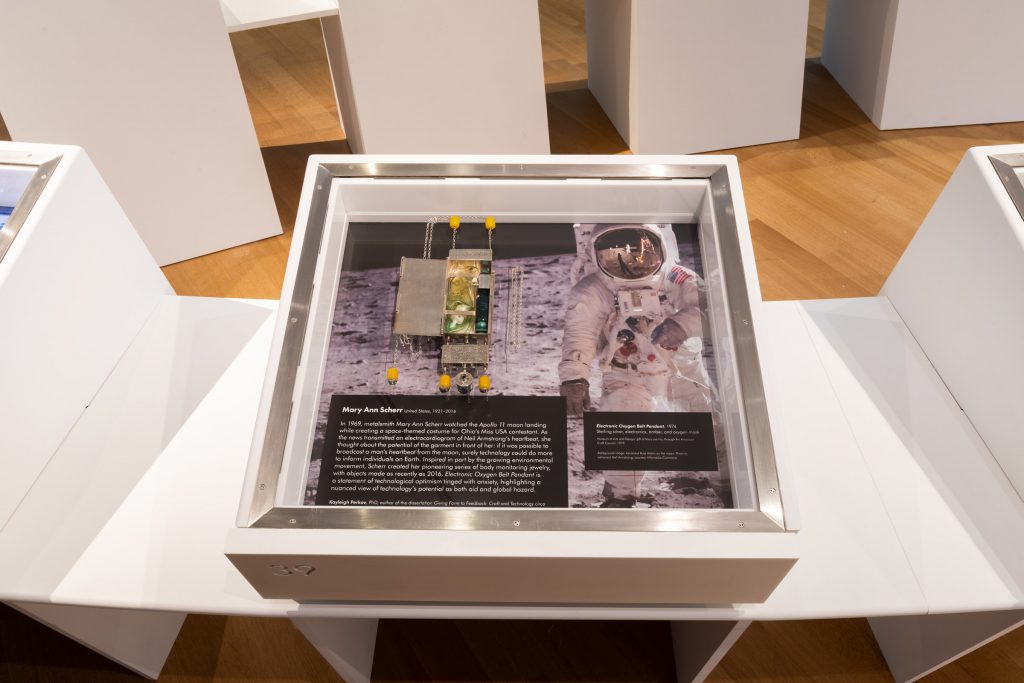A white display case shows some jewellery. The background is an image of an astronaut, featuring white text against black boxes.