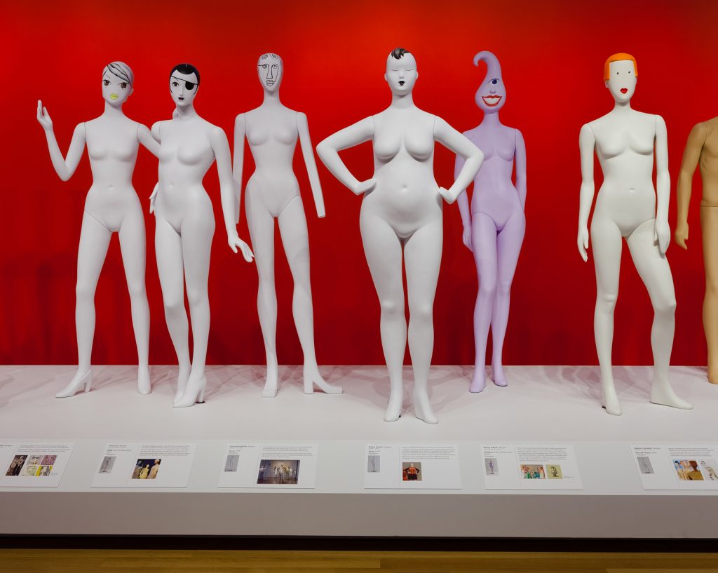 Installation photo of Ralph Pucci: The Art of the Mannequin, showing six mannequins. Five are white but one is purple with one eye. Other mannequins show limb differences; a mannequin wearing an eye patch and one with illustrated hair.