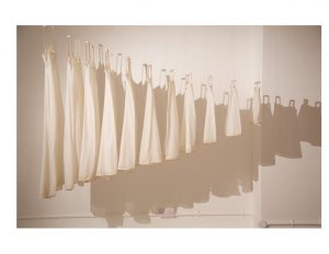 A row of white dresses, hung and ordered by size.