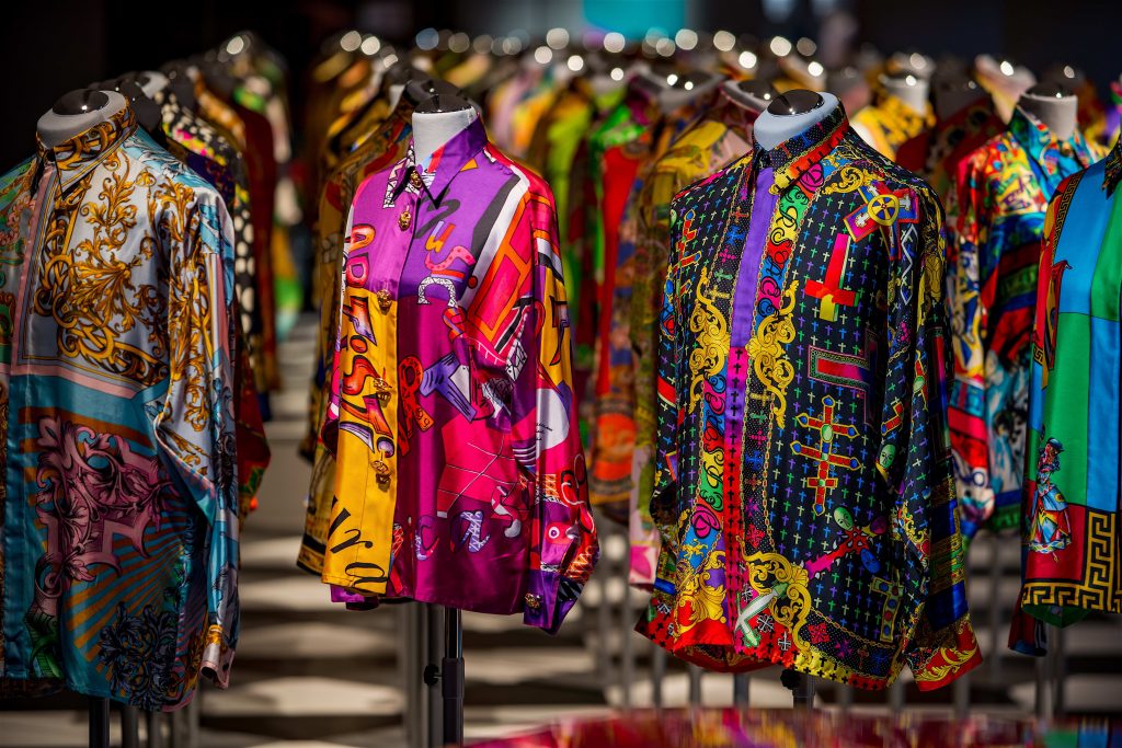 A view of many silk shirts, featuring different colours and prints, worn on tailor's dummies.