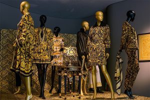 Six black and gold mannequins wear ornately patterned gold and black Greco inspired designs.