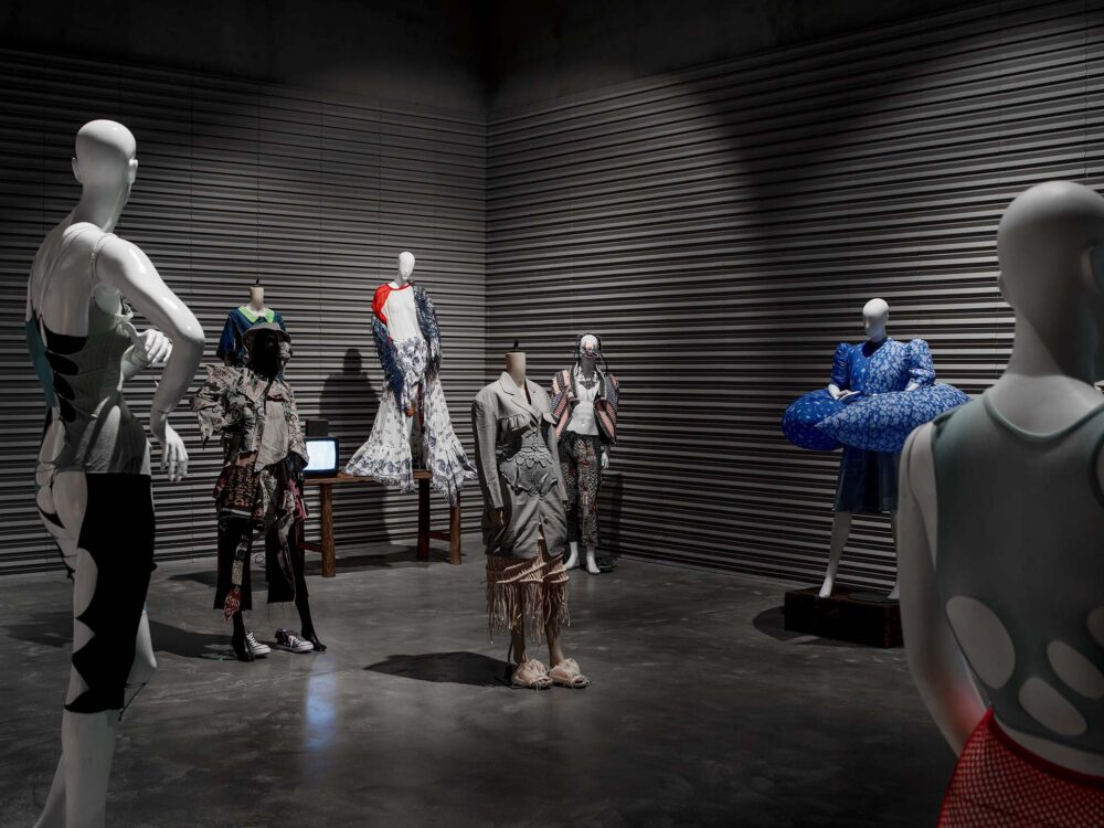 A group of mannequins on display., including one wearing an elongated dress and another wearing a blue inflated dress.