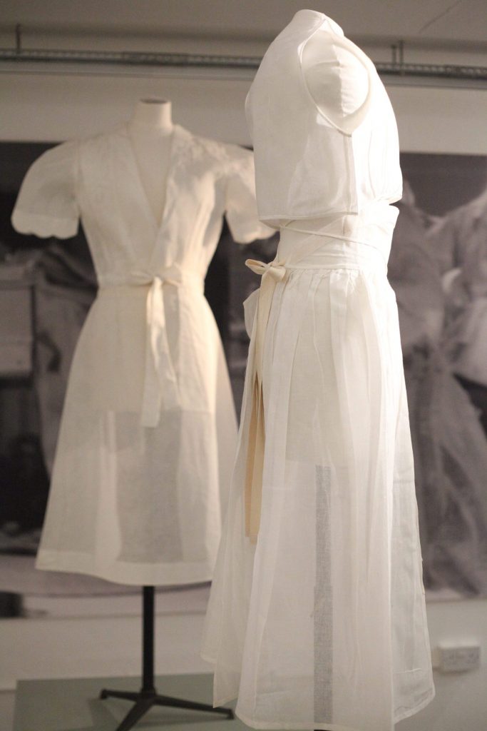 Two short-sleeved white dresses displayed on tailor's dummies.