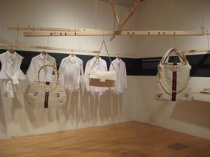 A row of white garments are hung on an ostensibly scale system against a white bag.