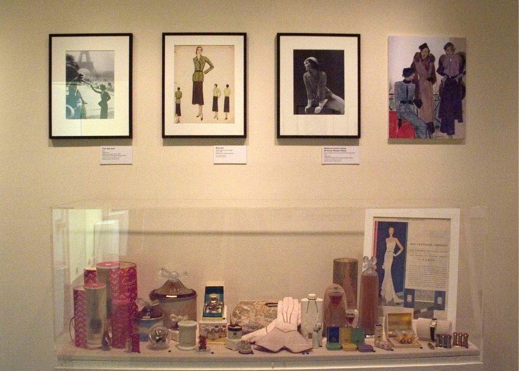 A display case of accessories sit beneath a row of monochrome photographs.
