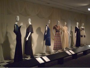 A row of dresses on white mannequins stand on display.