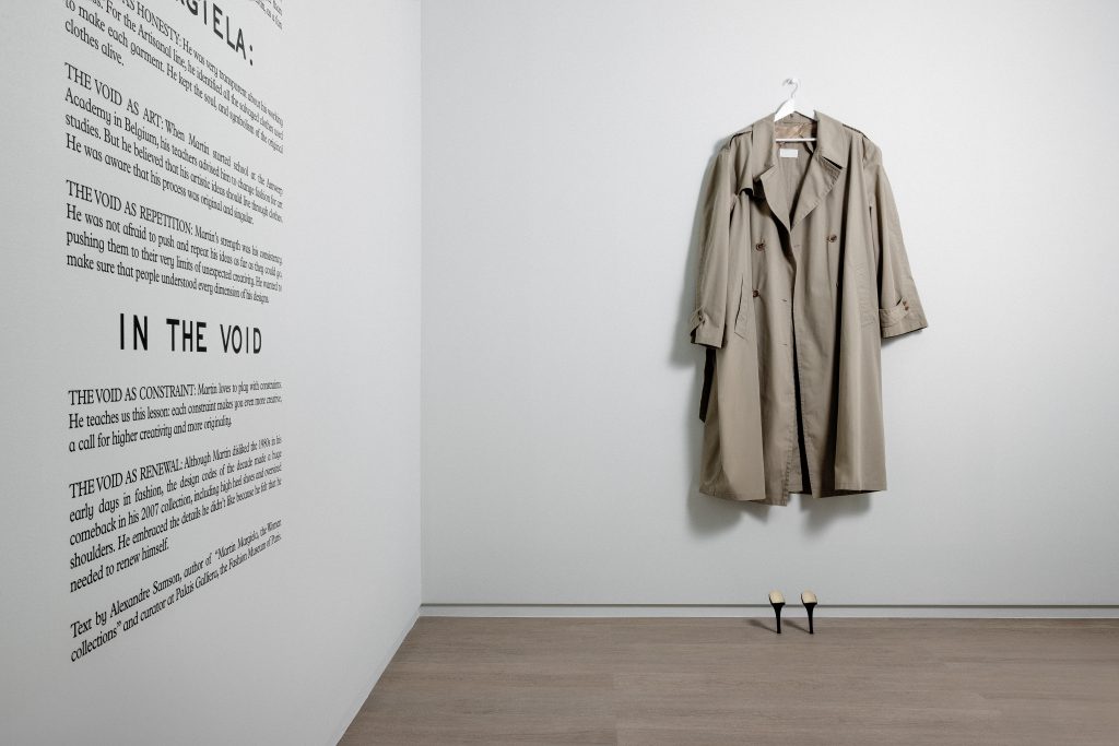 exhibition display of trench coat hung on wall