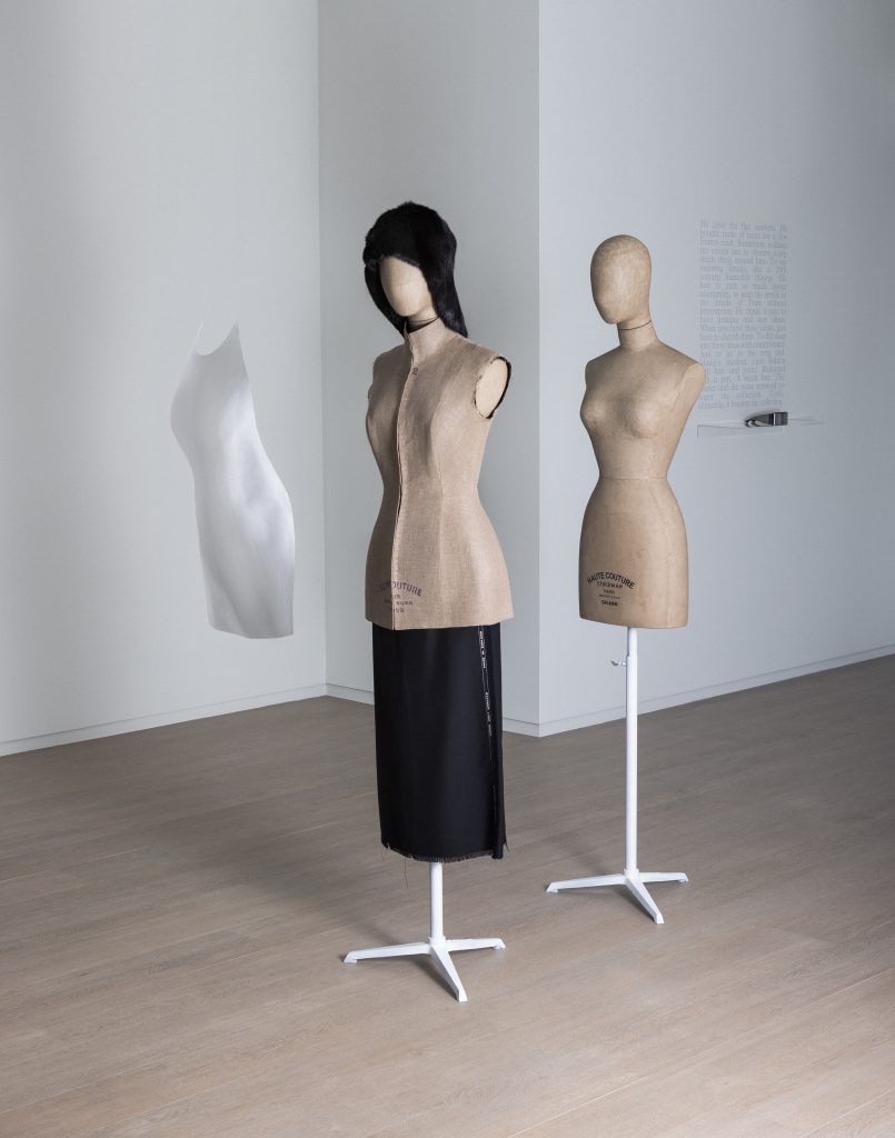 Exhibition display of mannequins partly dressed and floating garment in front