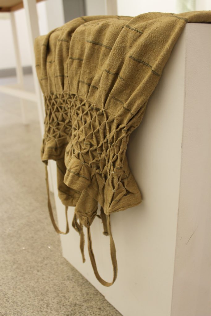 Woven brown and mustard coloured textile on display on a white box.