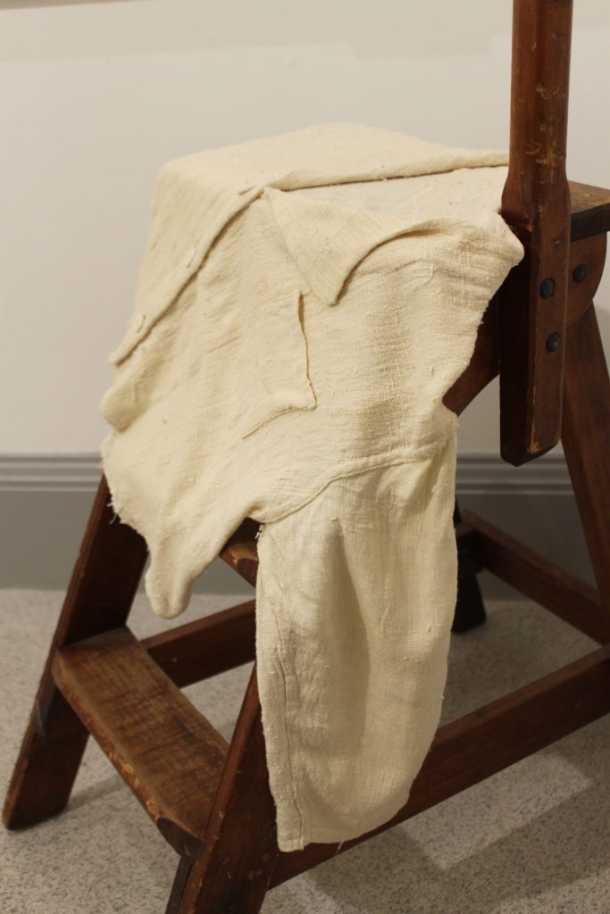 Cream top on display with sleeves and pockets on a wooden brown step.