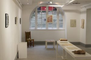 Installation room displaying drawings, prints and garments with objects from the Goldsmiths Textile Collection.