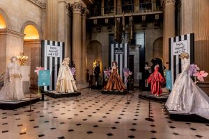 A collection of Vivienne Westwood dresses on display. White wedding dresses , brown and red dresses.