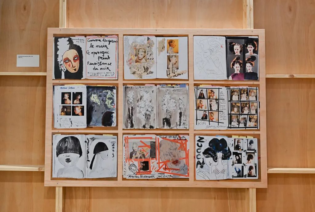 A display of sketches of fashion designs on a wooden backdrop