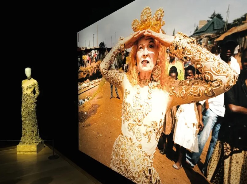 A mannequin wearing a full length gold dress featured beside an image of Viviene Westwood