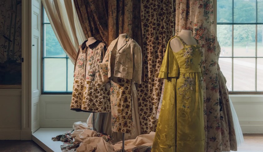 A trio of mannequins dressed in male and female historical clothing. Hues of yellow, purple and beige delight these garments.