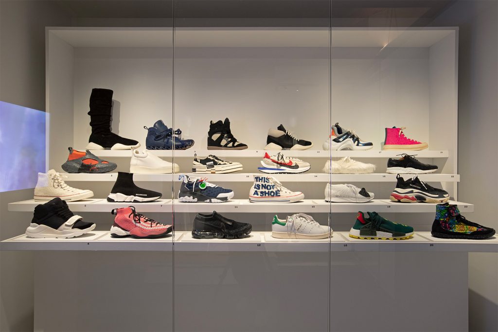 A display of different styles of sports shoes in colours of black, green,blue, white and pink.