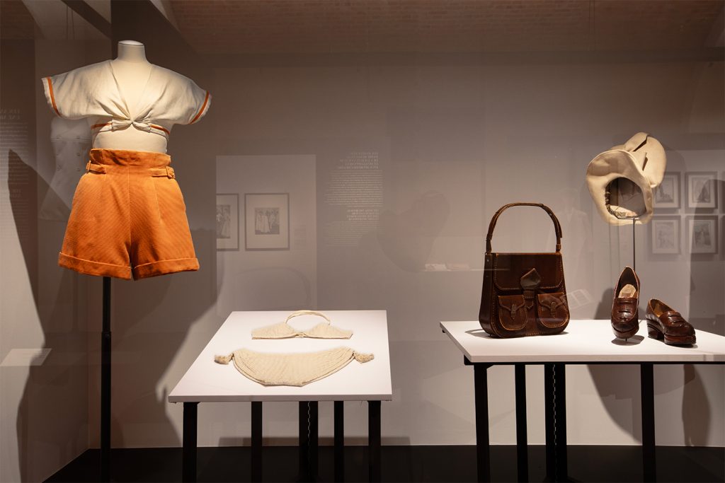 A display of historical swimwear, handbags and shoes in hues of brown, white and orange.