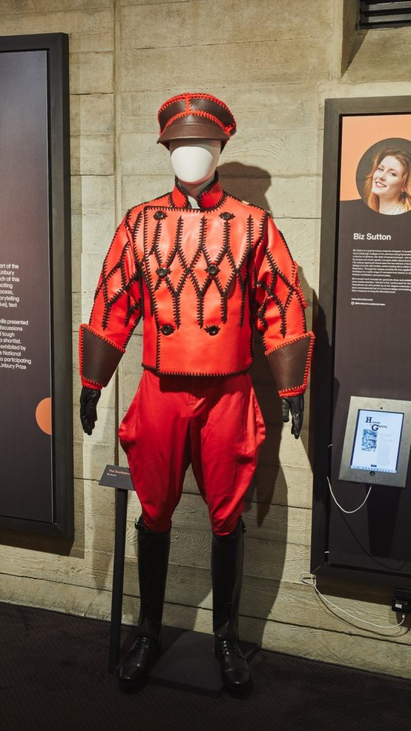 Costume for ‘The Duchess of Malfi’ by John Webster, designed and made by Biz Sutton. The costume is red with black detailing on the top and at the hips. The look is complete with a red hat and black boots.