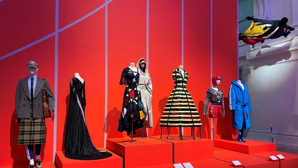 Sport inspired garments displayed on mannequins against a red backdrop.