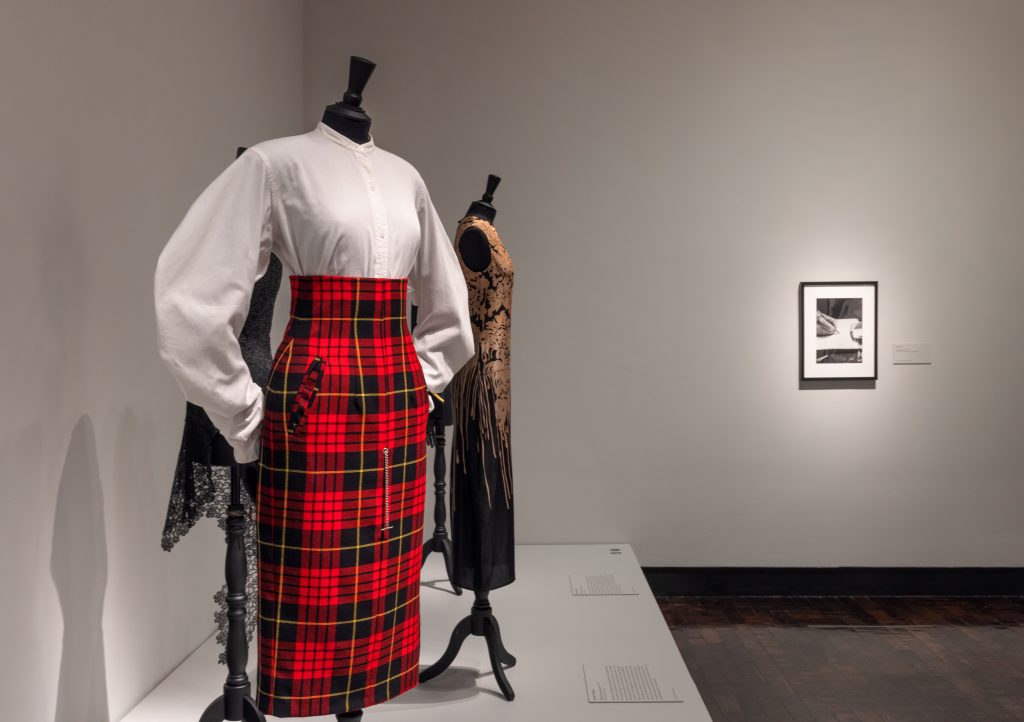 Female mannequin wearing McQueen's iconic red and black tartan skirt paired with a white skirt.