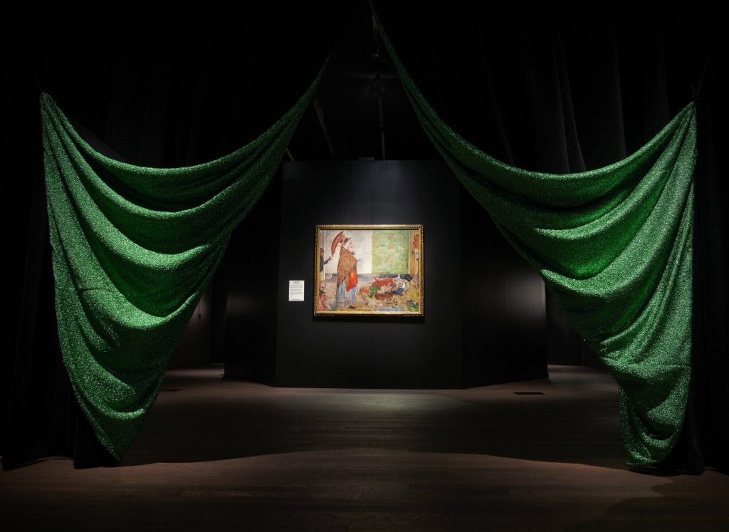 Green ruched curtains reveal a colourful piece of art displayed in the centre.