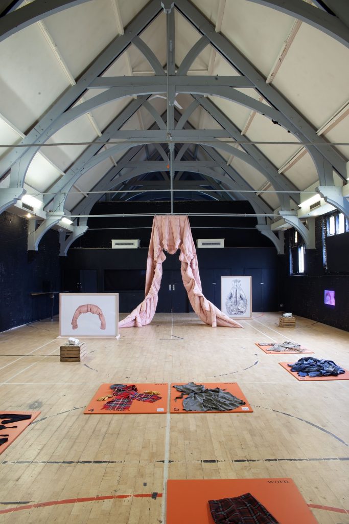 Installation in hues of dark blue, and pale pink. Several flat lays of installations placed around the floor.