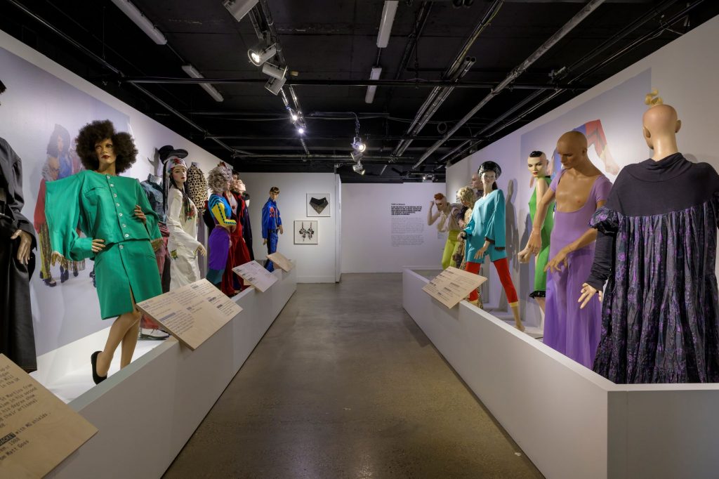 A collection of 80's style costumes, with big shoulder padded blazers and full length dresses. Colours include purple, red, green, and red.