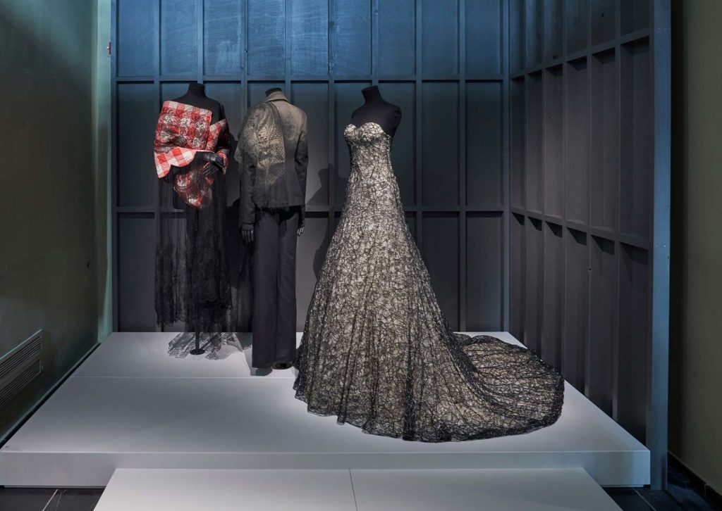 three mannequins all styled in elegant evening wear. Long silver/ white ballgown , all black suit and a black and red outfit.