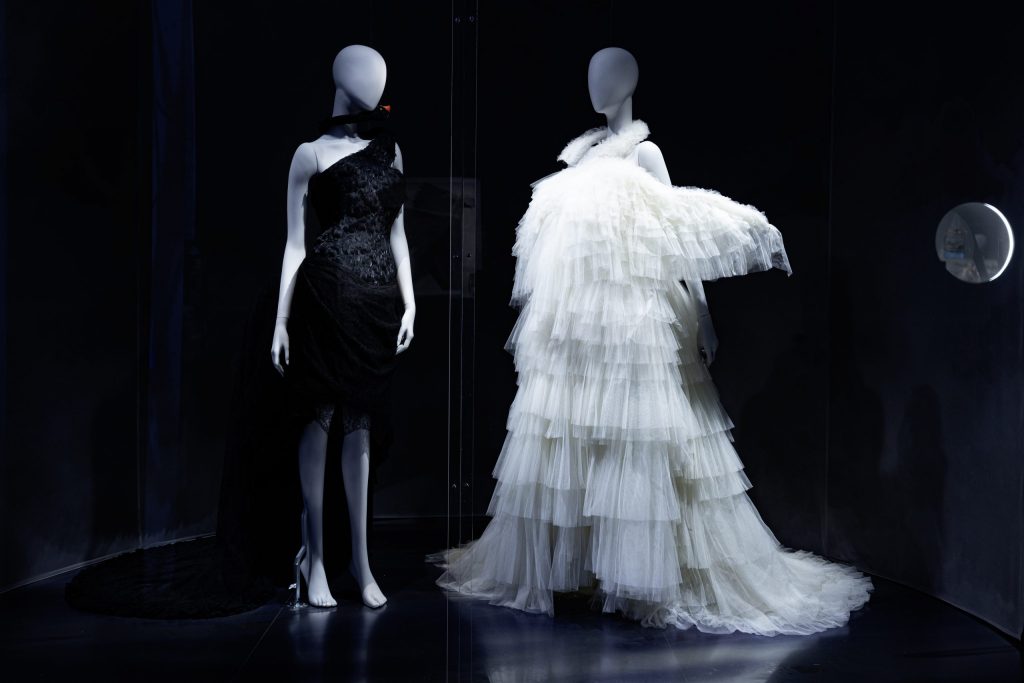 a pair of mannequins one with black and one with white feather/frilled dresses