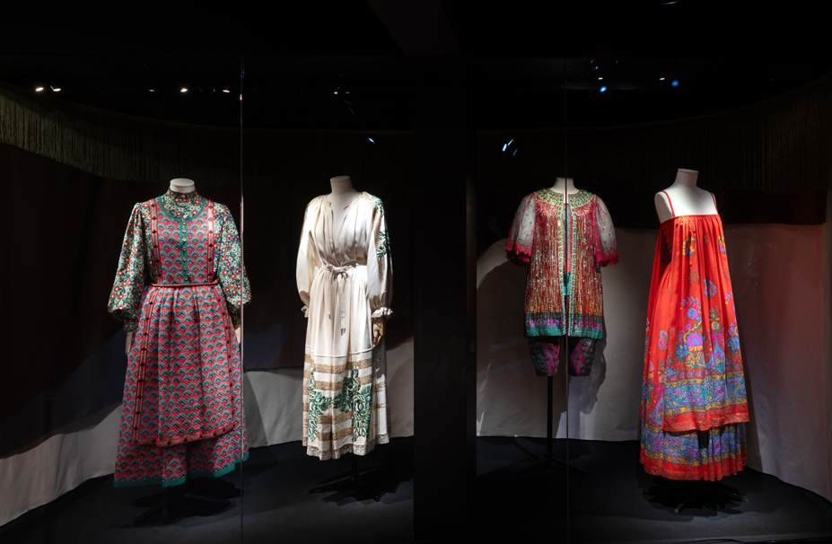 Four female mannequins wearing vintage dresses in hues of brown, red, white, red and blue.