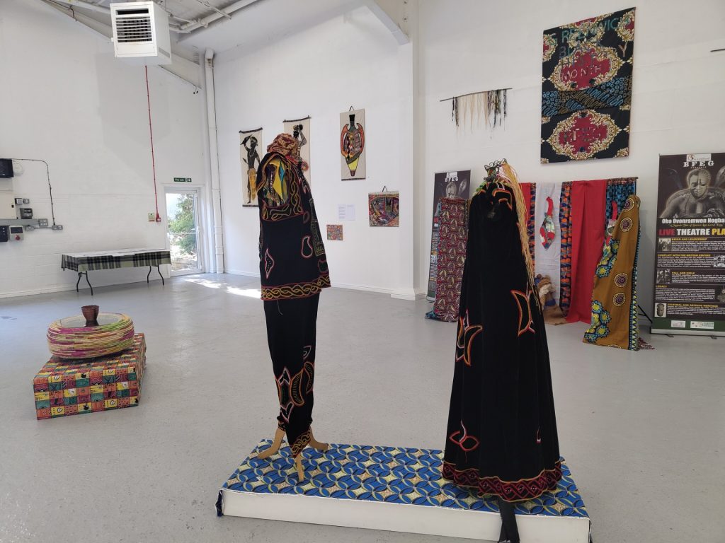 Two mannequins wearing floor-length garments in black and gold.