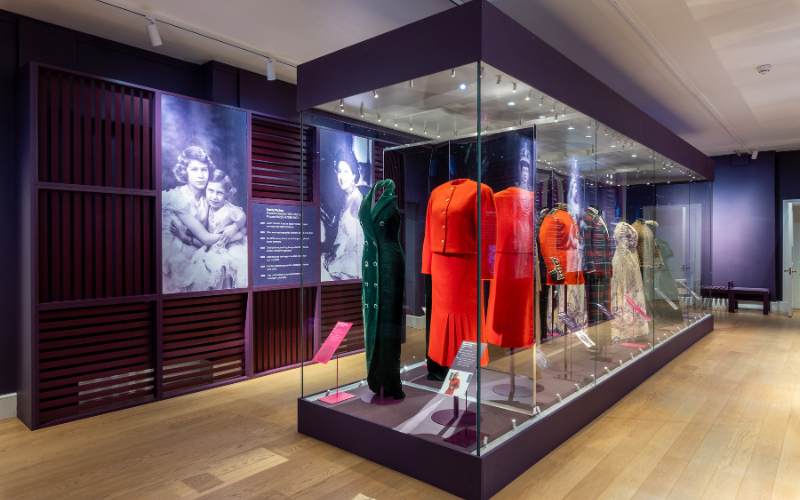 A collection of clothing from Lady Diana's collection. In hues of green, red and white outfits made up in dresses, blazers and skirts.