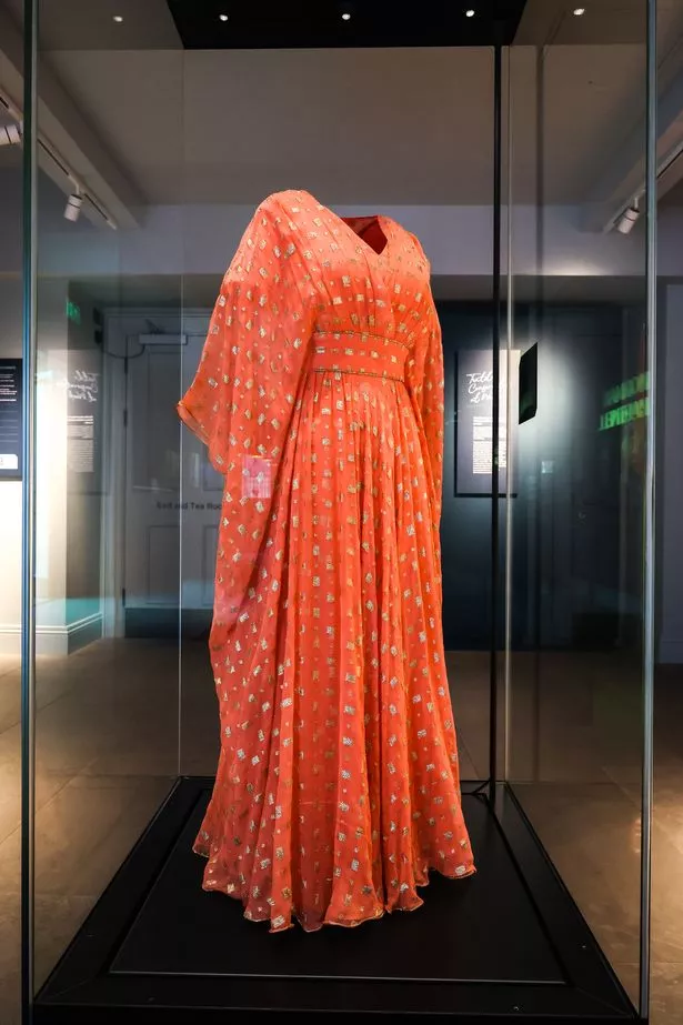 Orange floor length dress with gold speckles throughout. V-neck neckline with wise long sleeves.