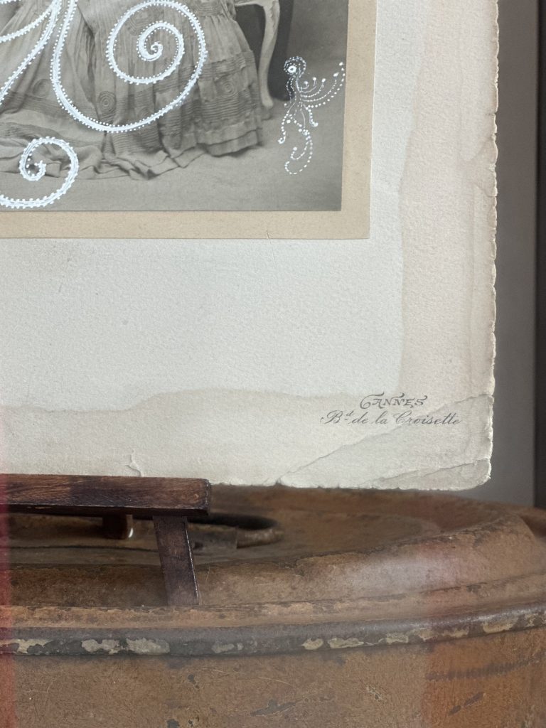 A corner of a black and white photograph on display, which is placed on top of a brown surface.