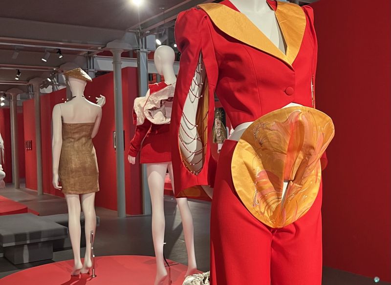 A trio of outfits of suits and dresses, in hues of gold, red and yellow.